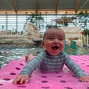 Noah a rejoint le concours — aidez-le/la à gagner de superbes lots ! baby, smiling, pool, water, indoor, floating_mat, swimsuit, child, happy, playful, recreation, leisure, water_sports, toddler, fun, paddle, relaxation, summer, splash, joy