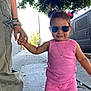toddler, child, pink_clothing, sunglasses, sidewalk, hand_holding, adult, outdoor, sunlight, vehicle, tree, happy, smile, hair_buns, necklace, casual_wear, urban, street, person, playful