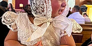 Anely is registered to the contest to win money with this photo: baby, child, lace, bonnet, dress, clapping, hands, church, pew, wood, background, people, celebration, portrait, cute, infant, religious, indoors, happy, event