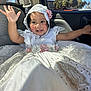 toddler, child, white_dress, lace, flowers, car_interior, sunlight, waving, smiling, hood, seatbelt, window, trees, blue_sky, embroidery, pink_flowers, happy, portrait, cute, indoors
