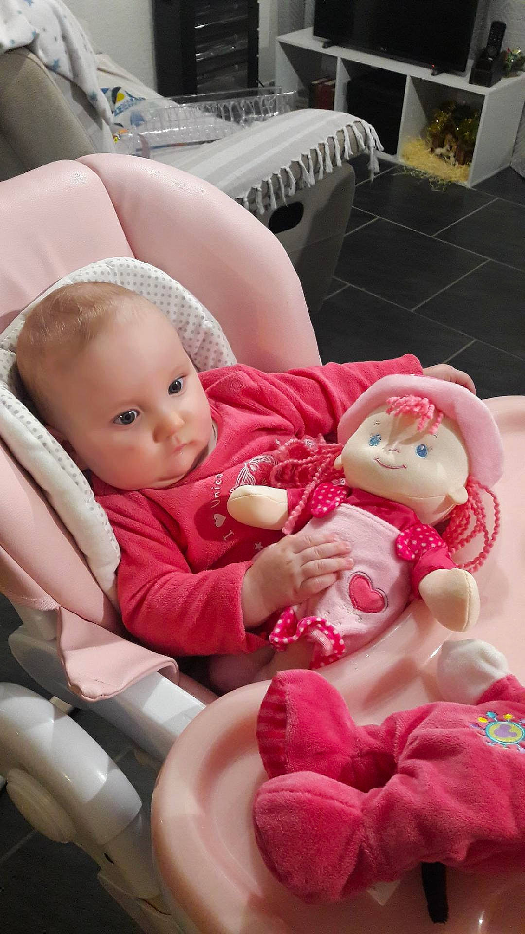 Elyana participe au concours pour gagner de l'argent avec cette photo : baby, baby_products, baby_toddler_clothing, car_seat, carmine, cheek, child, comfort, doll, happy, head, lap, person, pink, room, sitting, skin, toddler, toy, vertebrate