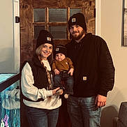 Daxton joined the competition — help win amazing prizes! family, baby, woman, man, beanie, casual_clothing, jeans, indoor, door, wooden_door, fish_tank, smile, holding_baby, portrait, people, home_interior, long_hair, facial_hair, happy, toddler