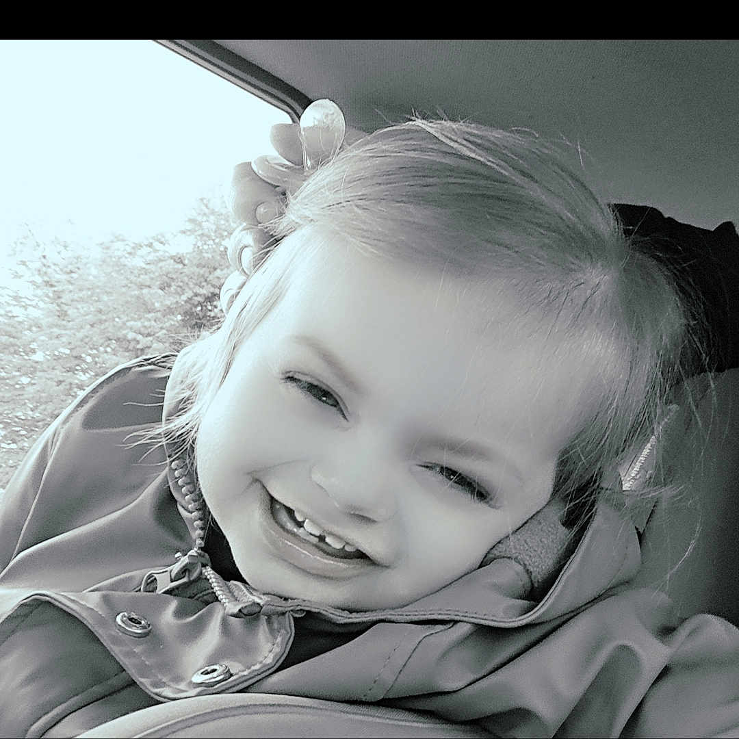 Kathalya a rejoint le concours — aidez-le/la à gagner de superbes lots ! baby, black_and_white, car_seat, child, clothing, cute, face, flower, hair, hand, happy, indoor, jacket, person, portrait, seat, smiling, toddler, window, young_child