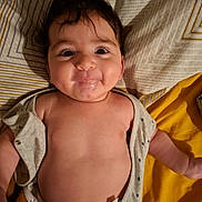 Adem participe au concours pour gagner de l'argent avec cette photo : baby, bedspread, child, chubby_cheeks, cute, diaper, expression, face, hair, indoors, infant, lying_down, mouth, onesie, pattern, person, playful, skin, smiling, young