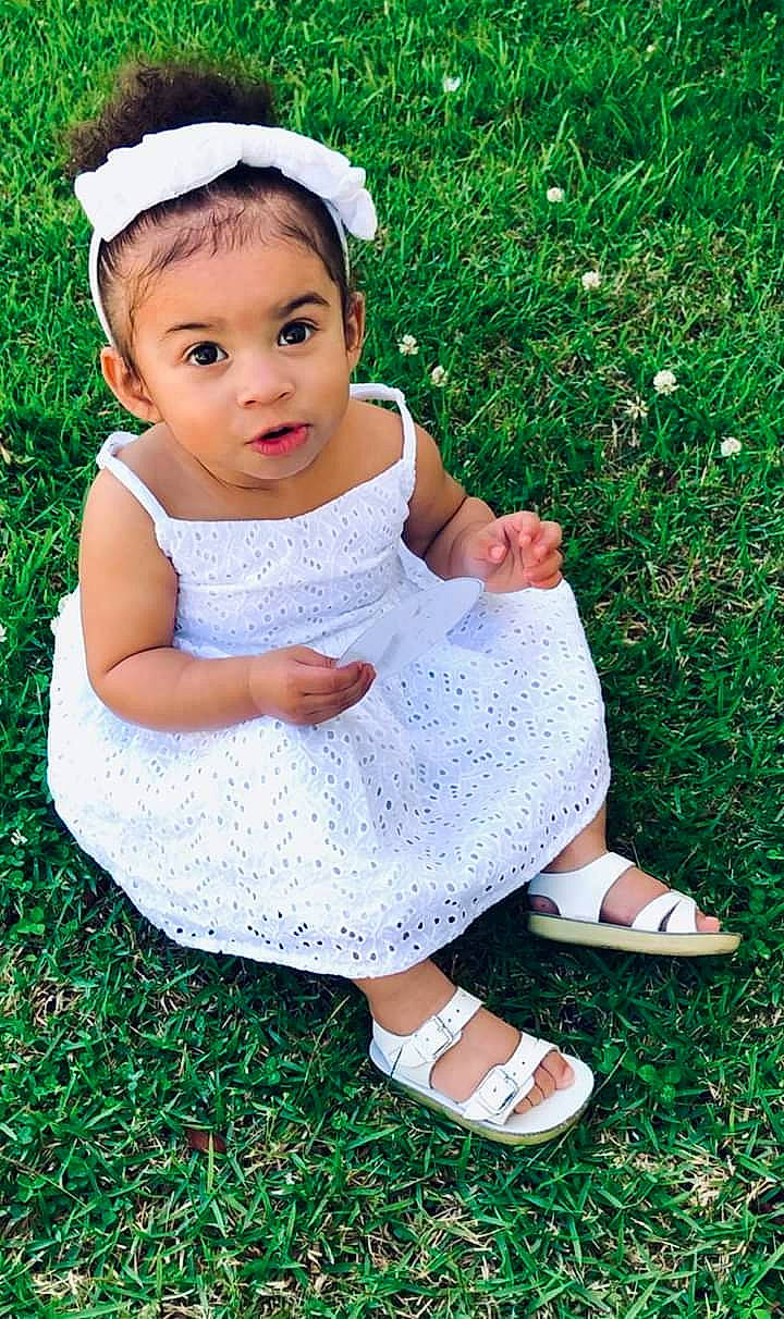 Armani E. joined the competition — help win amazing prizes! baby, baby_products, baby_toddler_clothing, child, design, dress, grass, hair_accessory, headband, headgear, pattern, person, sitting, smile, surprise, toddler