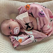 Raven is registered to the contest to win money with this photo: baby, blanket, child, clothing, comfort, cushion, cute, fabric, face, indoors, infant, lying_down, newborn, pacifier, person, pink, resting, sleeping, soft, wrapped