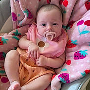 Raven is registered to the contest to win money with this photo: baby, pacifier, blanket, pink, strawberries, cherries, bib, flower, infant, cute, child, clothing, soft, relaxed, indoor, person, skin, legs, feet, hand