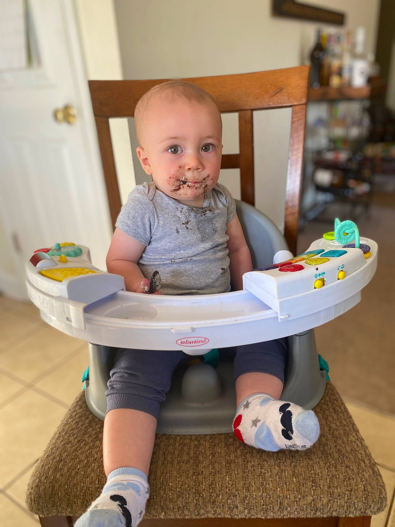 Brian is registered to the contest to win money with this photo: baby, baby_toddler_clothing, child, cleanliness, door, flooring, fun, human_leg, knee, person, plastic, play, room, sitting, sock, t_shirt, table, thigh, toddler, toy