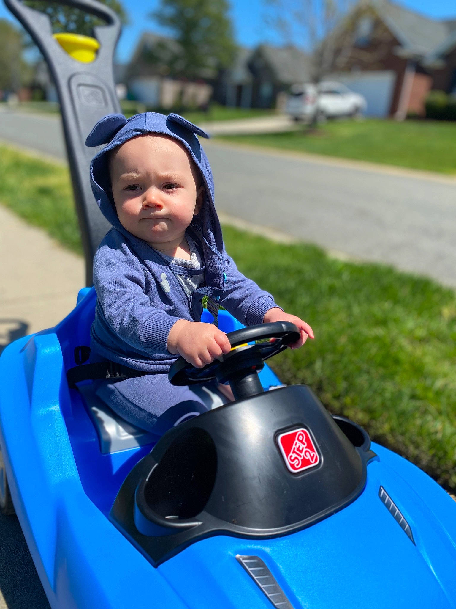 Brian is registered to the contest to win money with this photo: automotive_design, automotive_exterior, automotive_tire, blue, electric_blue, grass, headwear, helmet, leisure, motor_vehicle, outdoor_recreation, person, personal_protective_equipment, plant, recreation, sky, sports, tire, toddler, travel