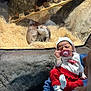 baby, newborn, pacifier, otter, aquarium, glass, enclosure, straw, rock, adult, holding, red_pants, white_sock, hat, sleeping, person, animal, display, portrait, visitor