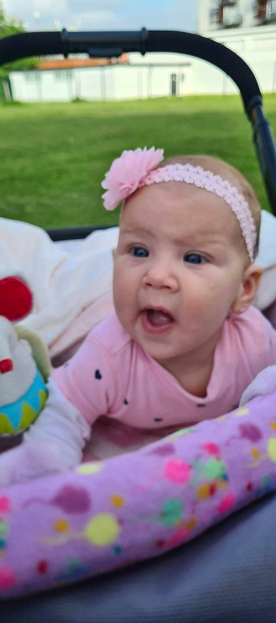 Aisha is registered to the contest to win money with this photo: baby, baby_toddler_clothing, cheek, chin, eye, eyelash, facial_expression, finger, grass, happy, iris, leisure, lip, mouth, nose, person, pink, plant, skin, smile