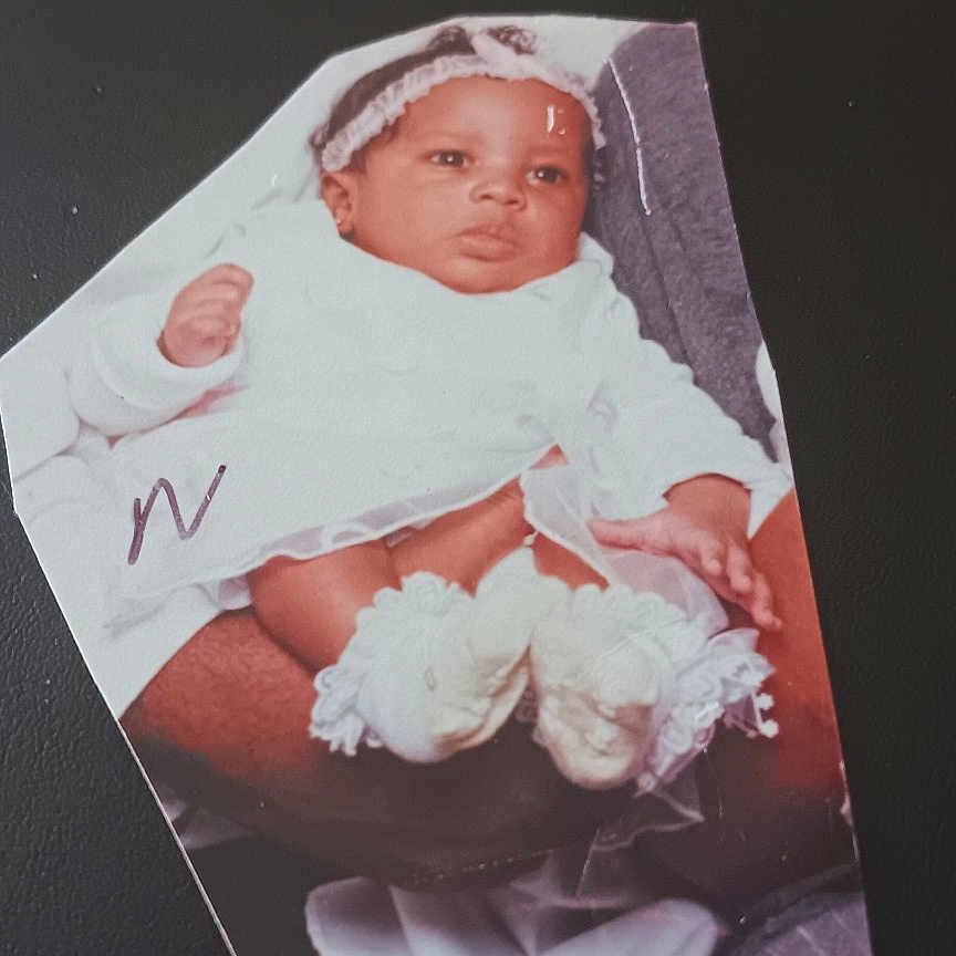 Nay'Omee is registered to the contest to win money with this photo: baby, infant, cutout_photo, white_clothing, headband, hands, feet, adult_hands, background, black_background, text_overlay, sentimental, portrait, clothing, infant_booties, photograph, keepsake, close_up, human, person