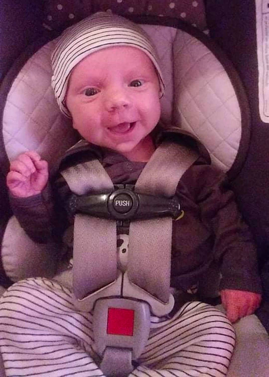 Drayden is registered to the contest to win money with this photo: auto_part, baby, baby_carriage, baby_products, cap, car_seat, cheek, child, comfort, happy, head_restraint, headwear, magenta, person, photograph, pink, purple, seat_belt, skin, smile