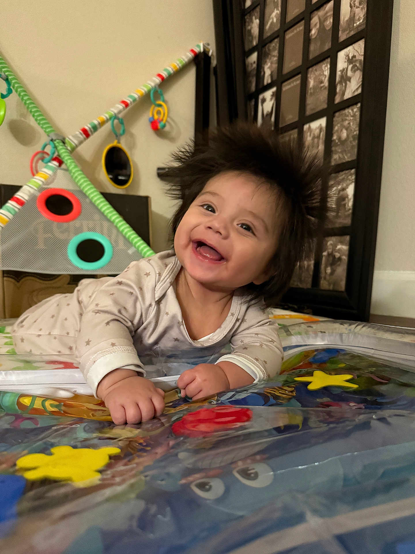 Eliseo is registered to the contest to win money with this photo: baby, smiling, play_mat, toy, indoor, child, happy, face, hands, clothing, home, decor, photo_frame, furniture, colorful, cute, infant, joyful, lying_down, portrait