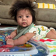 Eliseo is registered to the contest to win money with this photo: baby, child, infant, hair, play_mat, couch, living_room, colorful, curious, face, eyes, clothing, patterned, lying_down, indoors, soft_lighting, portrait, cute, young, expression
