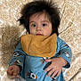 Eliseo is registered to the contest to win money with this photo: baby, child, infant, face, hair, wide_eyes, bib, blue_clothing, rocket_print, hand, cushion, patterned_background, lying_down, portrait, indoors, cute, young, expression, soft_lighting, fabric