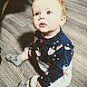 baby, child, infant, sitting, portrait, indoors, floor, wood_floor, pajamas, blue_clothing, socks, cartoon_pattern, winter_theme, wide_eyed, looking_up, sunlight, shadow, adorable, home, photography