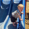 toddler, child, slide, playground, outdoor, sunlight, blue_slide, playing, happy, climbing, summer, daytime, grass, woodchips, casual_clothing, shorts, tshirt, barefoot, fun, park