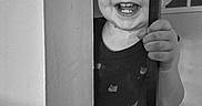 Owen Swartz joined the competition — help win amazing prizes! toddler, child, smiling, laughing, portrait, black_and_white, indoors, doorway, doorframe, hand, teeth, face, eyes, clothing, overalls, standing, home, interior, playful, happy