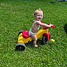 toddler, child, diaper, tricycle, toy, grass, outdoor, sunny, summer, play, happy, smile, water_pool, barefoot, greenery, playtime, young_child, fun, daylight, plastic_toy