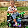 toddler, child, toy_truck, outdoor, grass, fence, cloudy_sky, footwear, shorts, tshirt, play, summer, green, black, purple, happy, cute, person, yard, daylight