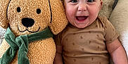 Brinley is registered to the contest to win money with this photo: baby, infant, smiling, onesie, plush_toy, dog_pillow, green_scarf, pumpkin_design, couch, cushion, happy, cute, indoor, child, person, seated, soft_texture, cozy, portrait, relaxed