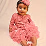 baby, child, pink_dress, headband, flower, sitting, cute, portrait, infant, soft_background, happy, smile, barefoot, tutu, lace, young_child, indoors, one_person, fashion, adorable