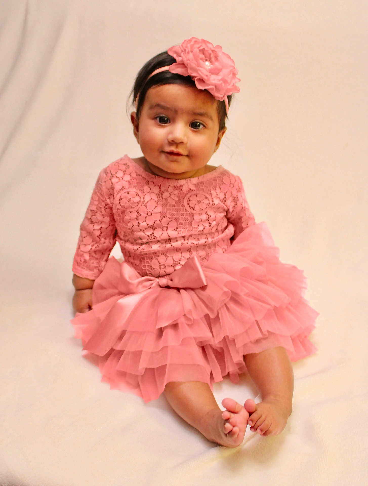 Arya joined the competition — help win amazing prizes! baby, child, pink_dress, headband, flower, sitting, cute, portrait, infant, soft_background, happy, smile, barefoot, tutu, lace, young_child, indoors, one_person, fashion, adorable