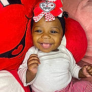 Azani joined the competition — help win amazing prizes! baby, bow, child, cozy, cute, face, hand, happy, headband, indoors, infant, joyful, plush_toy, portrait, red, sitting, smiling, soft_texture, striped_pants, white_clothing