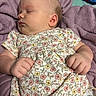 baby, sleeping, infant, portrait, floral_dress, blanket, purple_blanket, lying_down, peaceful, closed_eyes, face, hands, fists, indoors, cozy, bed, soft_lighting, newborn, resting, child