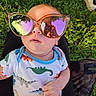 Milo is registered to the contest to win money with this photo: baby, casual, child, clothing, colorful, cute, dinosaur_onesie, face, grass, hand, head, infant, nature, outdoor, person, portrait, reflection, sitting, sunglasses, sunlight