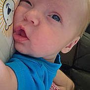 Milo is registered to the contest to win money with this photo: baby, bear_design, blue_eyes, blue_shirt, child, close_up, couch, cute, expression, face, holding, indoor, infant, light_hair, pattern, person, pillow, portrait, skin, snuggling