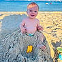 baby, beach, sand, ocean, toy, smiling, child, sunlight, sand_toy, barefoot, summer, vacation, outdoor, play, happy, water, sandcastle, nature, fun, toddler