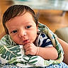 Adrian is registered to the contest to win money with this photo: baby, newborn, infant, blanket, hand, face, eyes, curly_hair, indoor, person, child, cute, portrait, skin, expression, holding, striped_clothing, comfort, soft, young