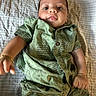baby, infant, child, portrait, lying_down, blanket, striped_blanket, green_outfit, clothing, buttoned_shirt, pineapple_pattern, face, eyes, cheeks, hands, arms, indoor, closeup, looking_at_camera, photography
