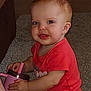 Lilliana is registered to the contest to win money with this photo: baby, child, infant, onesie, sippy_cup, carpet, indoor, cute, smiling, sitting, young_child, red_clothing, holding, drinkware, playful, face, person, skin, head, earrings
