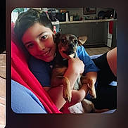 Nani is registered to the contest to win money with this photo: boy, dog, smiling, couch, blanket, indoors, kitchen, arm, face, pet, child, casual_clothing, happy, holding, furniture, tile_floor, shorts, young, cozy, portrait