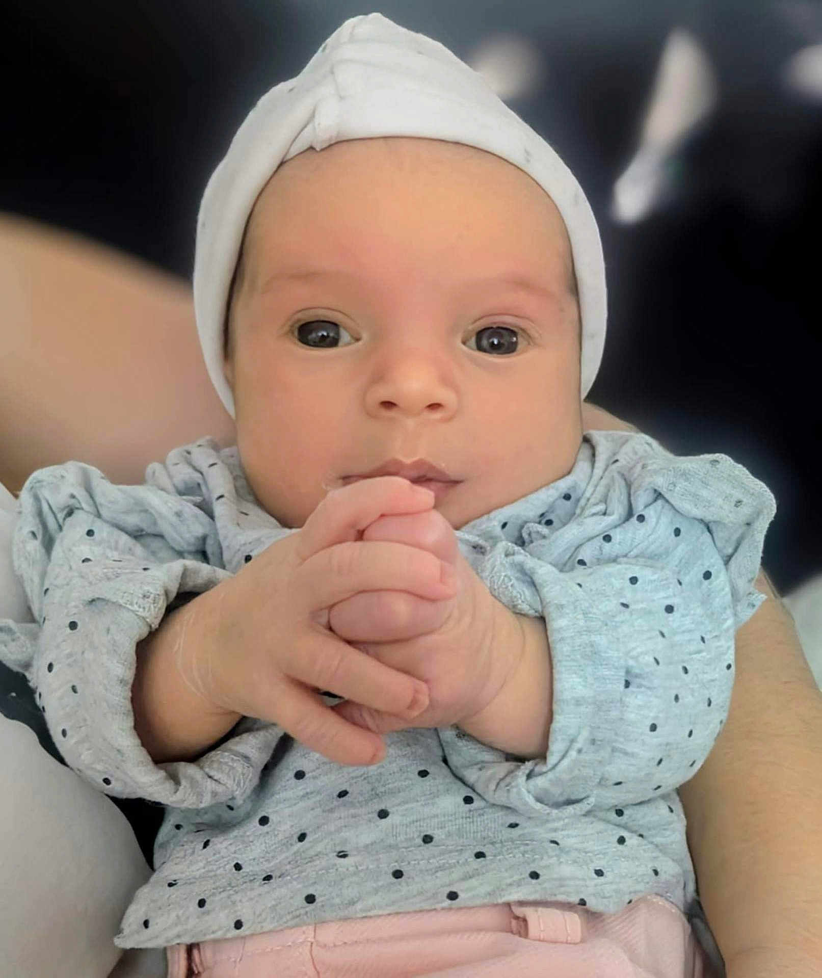 Maëlia a rejoint le concours — aidez-le/la à gagner de superbes lots ! baby, infant, face, hands, hat, clothing, polka_dot, cute, child, portrait, expression, skin, person, newborn, casual_wear, sitting, looking, indoors, soft_lighting, human