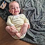 baby, blanket, candid, child, cozy, cute, face, feet, floor, hand, happy, indoor, infant, onesie, person, playful, smile, texture, toy, wooden_floor