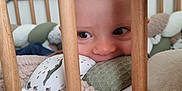 Gabriel a rejoint le concours — aidez-le/la à gagner de superbes lots ! baby, child, cozy, crib, cushion, cute, eyes, fabric, face, indoor, infant, nursery, pattern, peek, playful, smile, soft, texture, wood, wooden_bars