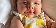 Reya is registered to the contest to win money with this photo: baby, infant, smile, face, arm, clothing, pillow, blanket, skin, cute, happy, young_child, indoors, closeup, person, child, sleepwear, resting, cheeks, soft