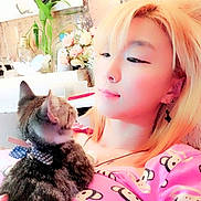 Yeulmu is registered to the contest to win money with this photo: person, cat, kitten, selfie, indoor, pink, pajamas, monkey_print, blonde_hair, flowers, necklace, earrings, bow_decor, fairy_lights, cozy, pet_owner, pillow, decoration, bow_tie, close_up