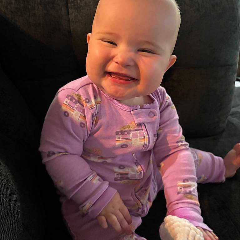 Liliana A. is registered to the contest to win money with this photo: baby, child, comfort, couch, cozy, cute, expression, face, happy, head, home, indoors, infant, pajamas, person, purple_clothing, sitting, smiling, tooth, young