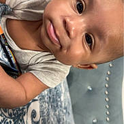 Zahkai is registered to the contest to win money with this photo: baby, infant, close_up, face, eyes, smile, blanket, pacifier, arm, tattoo, book, bed, fabric, pattern, indoor, person, cute, skin, head, clothing