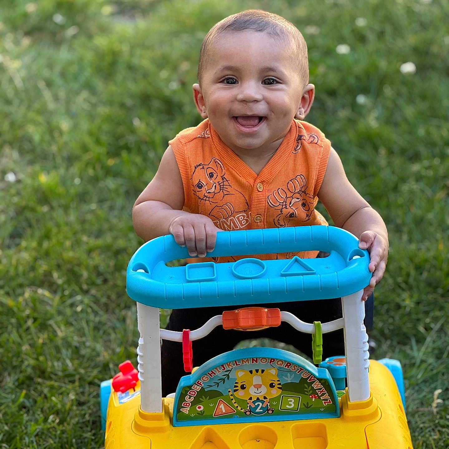 Zahkai is registered to the contest to win money with this photo: baby, blue, child, cute, fun, grass, green, happy, orange_clothing, outdoor, park, person, play, portrait, smiling, summer, toddler, toy, walker, yellow