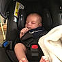 baby, infant, sleeping, car_seat, black, blanket, foot, toes, child, indoors, seatbelt, safety, peaceful, rest, cute, small, person, soft, comfort, nap