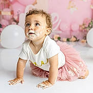 Ophelia is registered to the contest to win money with this photo: toddler, child, baby, cake, frosting, pink_tutu, white_shirt, crawling, birthday, party, balloons, curly_hair, messy, cute, celebration, indoor, portrait, smudged_face, happy, curious