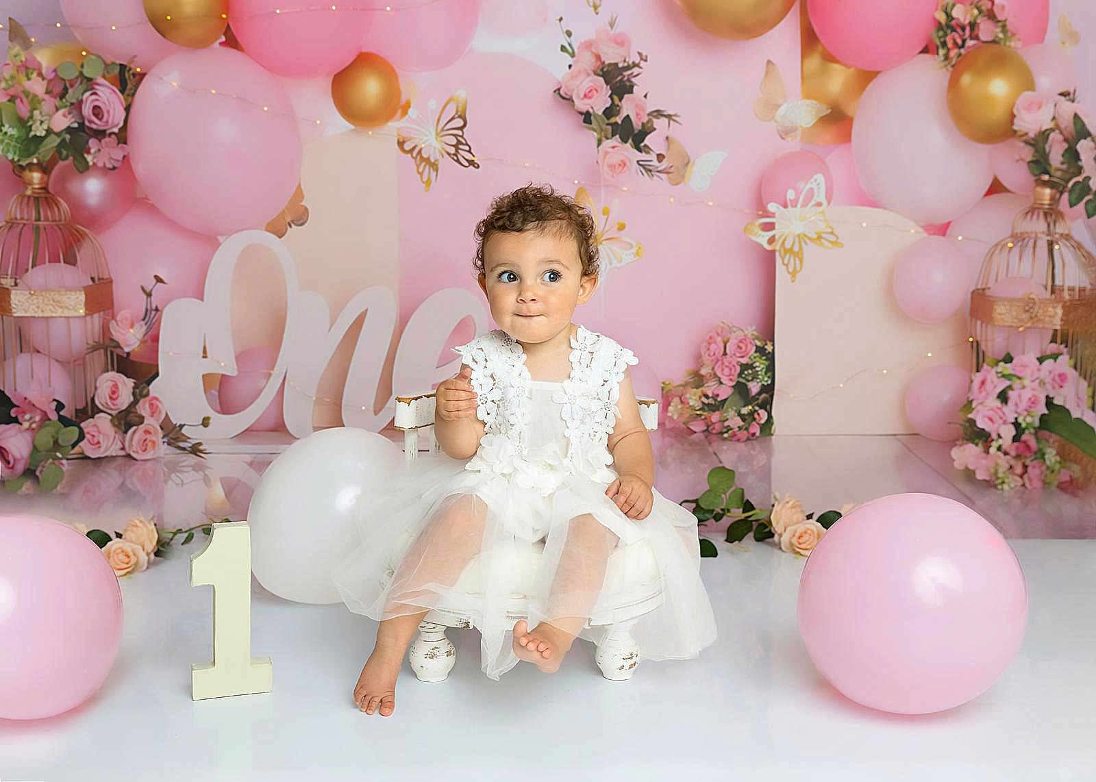 Ophelia joined the competition — help win amazing prizes! toddler, child, white_dress, balloons, pink_balloons, gold_balloons, birthday, one_year, flowers, decorations, chair, celebration, portrait, cute, smiling, indoor, party, curly_hair, baby, festive