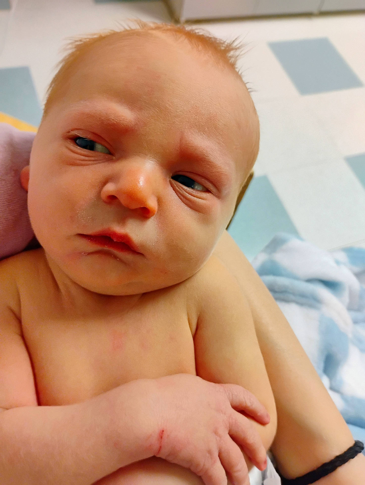 arm, baby, blanket, casual, closeup, curious, expression, face, floor, hand, holding, human, indoors, infant, newborn, person, portrait, skin, skin_texture, young_child