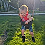toddler, child, swing, playground, grass, sunlight, happy, smiling, outdoor, summer, casual_clothing, black_shoes, red_tank_top, denim_shorts, park, play_equipment, joyful, fun, daylight, nature